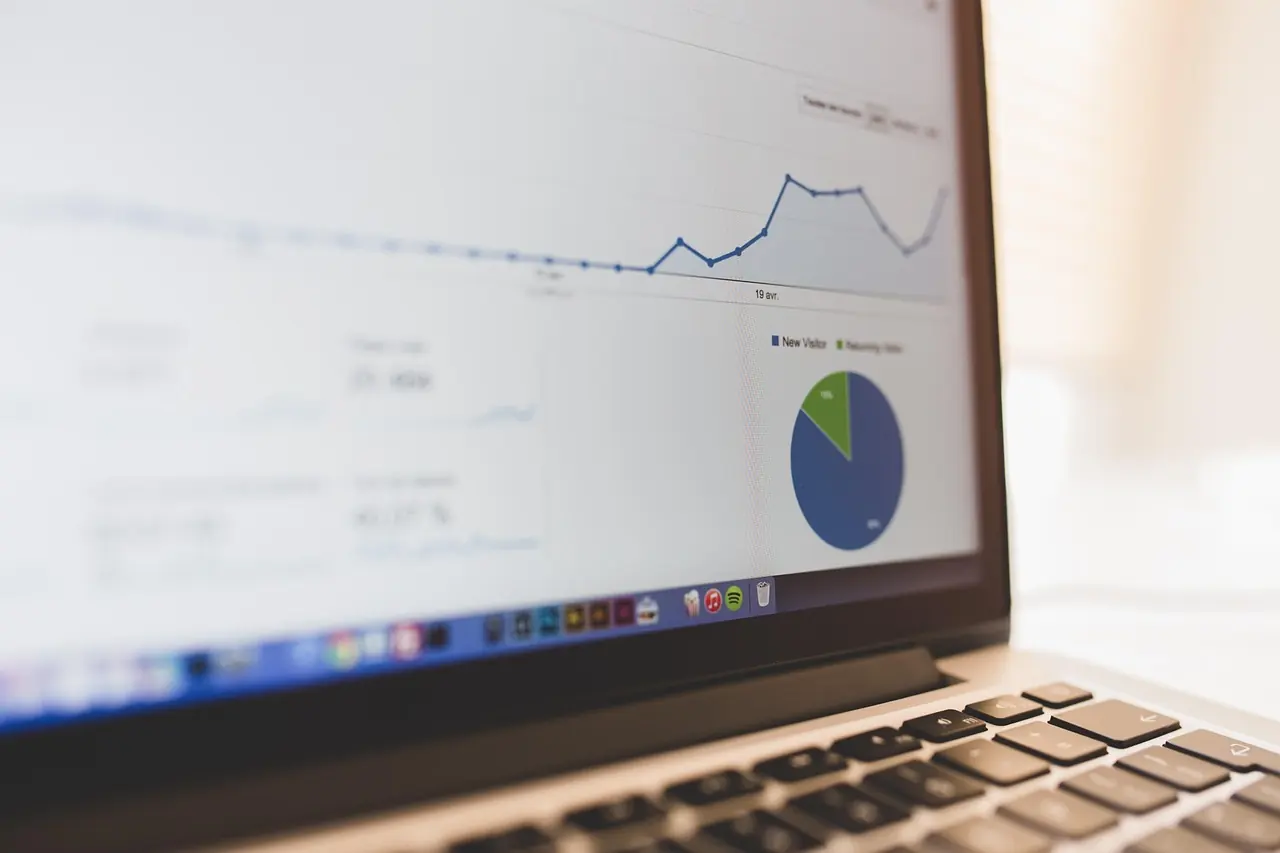 A laptop showing a web analytics dashboard with a traffic chart and a breakdown by source