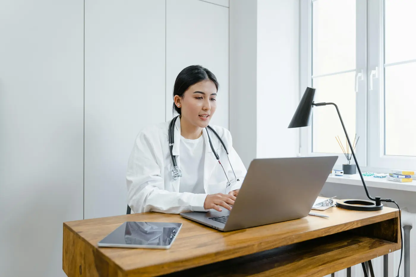 A doctor working at a laptop in a consulting room