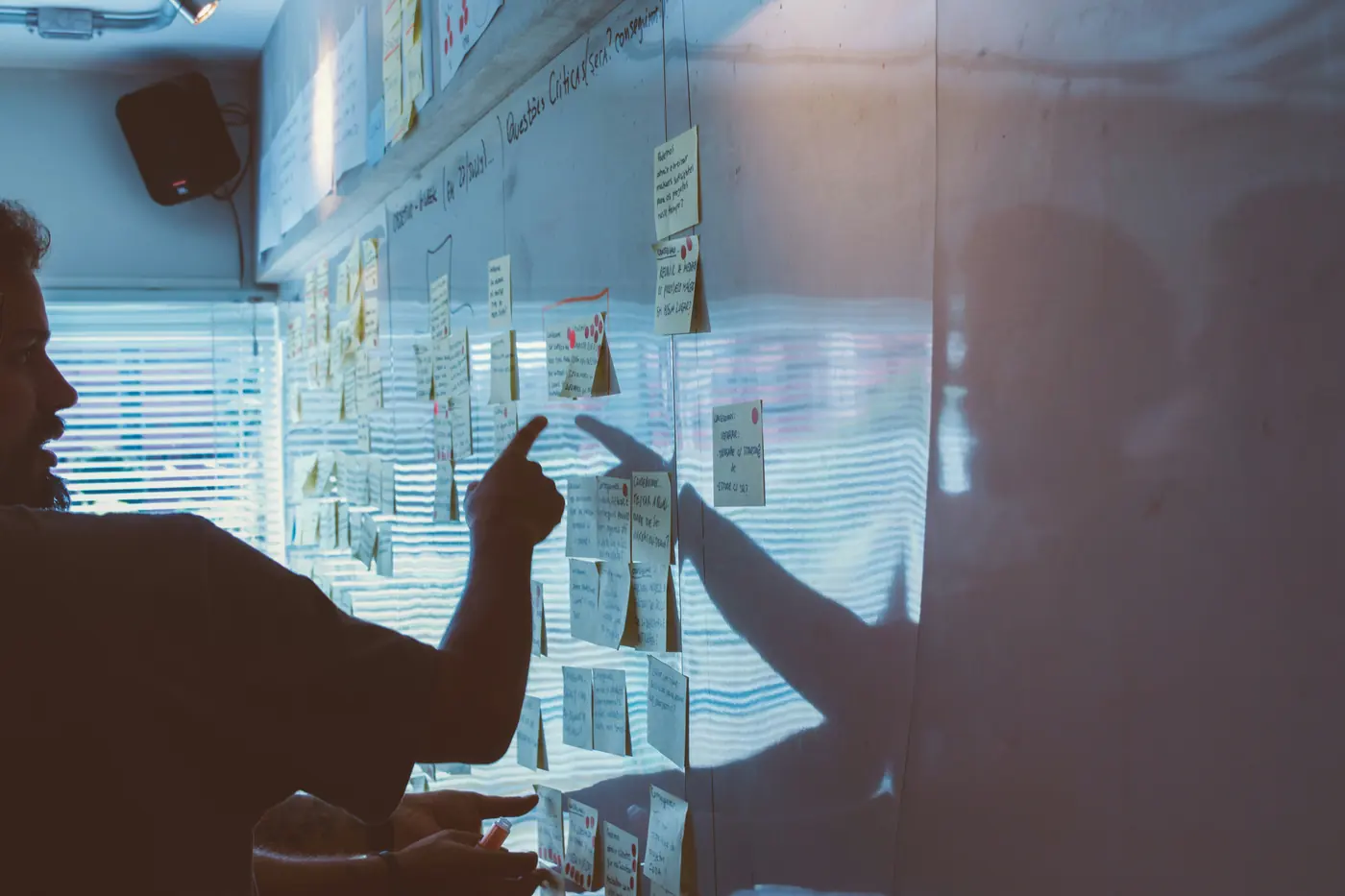 A team in silhouette at a glass wall covered in notes