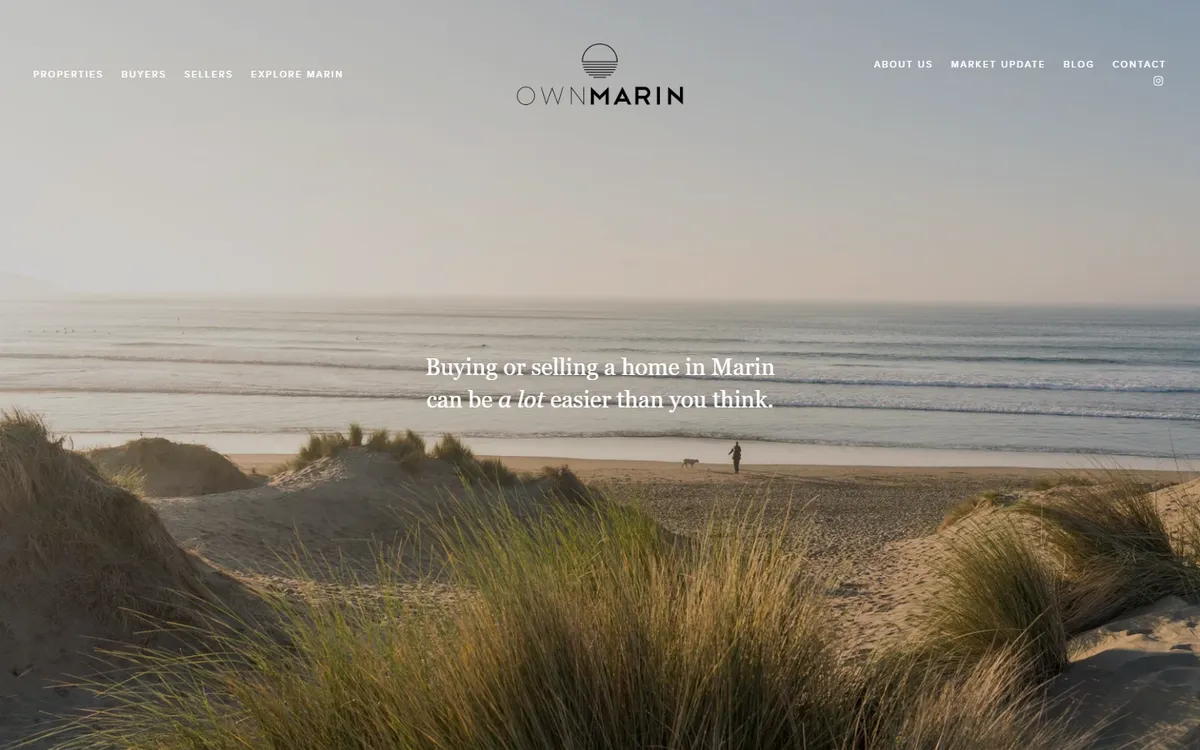 Own Marin home page: a wide photo of a beach with dune grass and a person walking a dog at the waterline, the Own Marin logo centred at the top between two small menus, and the line Buying or selling a home in Marin can be a lot easier than you think